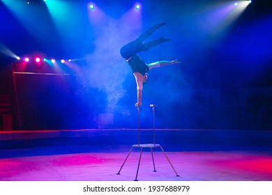 A man of athletic build performs complex gymnastic exercises in the circus arena