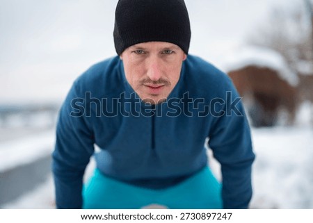 Man in athletic clothes looking determined while training outdoors during winter