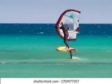 Man in Atlantic ocean  riding a hydrofoil surfboard using a hand held foil wing. Fuerteventura, Canary Islands, Spain.