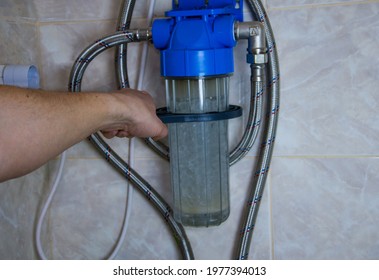 A man attaches a home water softener to the wall with a special key. Close-up of a compact water softening and filtration system. Universal water softening system for home