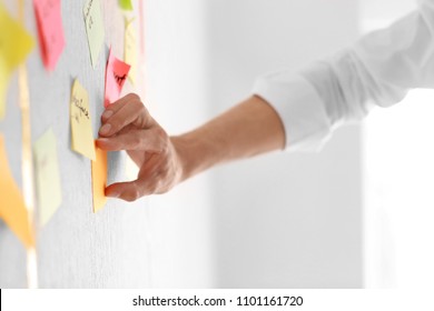 Man attaching sticky note to scrum task board in office - Shutterstock ID 1101161720