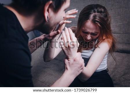 A man attacks a woman, domestic violence. Drunk husband beats his wife. An aggressive man hits her with a belt and pulls her hair. The frightened girl is crying. The perpetrator shouts at the victim.