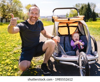 A man with baby in jogging stroller running outside in summer season