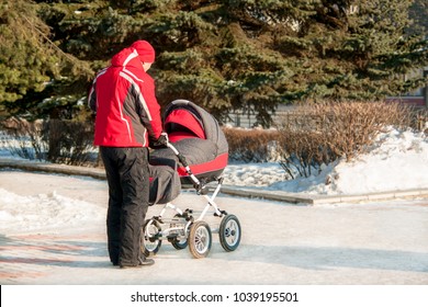 Man With Baby Stroller Walks Through The Winter Park.