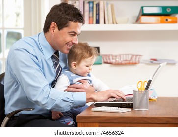 Man With Baby Working From Home Using Laptop