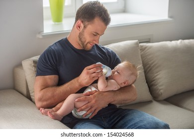 Man with baby. Young muscular man feeding little baby