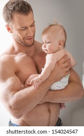 Man With Baby. Young Muscular Man Holding Baby In His Hands And Smiling