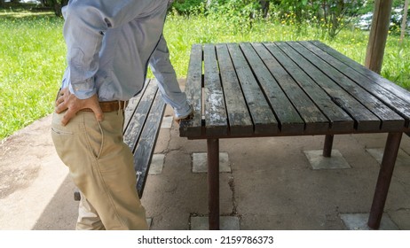 A man with back pain.Rest on a park bench.