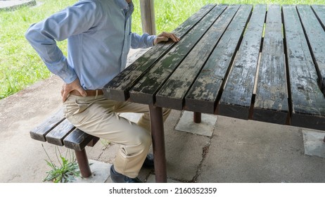 A man with back pain.Rest on a park bench.
