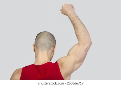 Man from the back raising his arm and fist. Fit bodybuilder with fist up in the air. Bald shaved man with muscles protesting. - Powered by Shutterstock