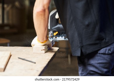 a man from the back saws off a piece of wood with a jigsaw