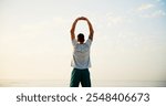 Man, back and stretching with fitness by beach for workout, breathing exercise or health and wellness in nature. Active, male person or runner with warm up for training or fresh air by ocean coast