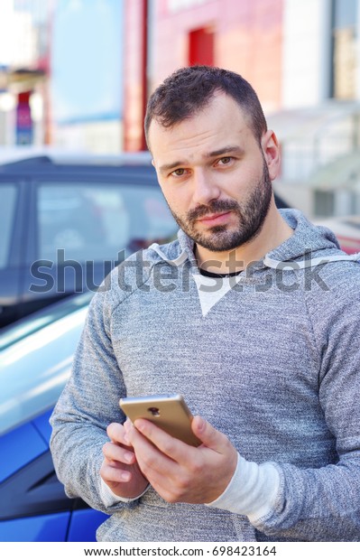 Man in the background
of a car with a phone in his hands. Call the car through the
Internet taxi service.