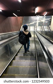 A man with a backpack down the escalator on foot
