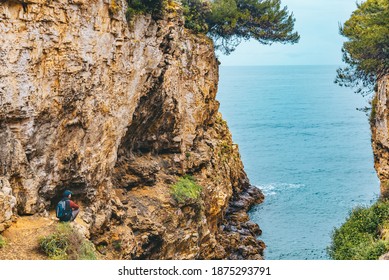 man with backpack at edge of the cliff looking at sea