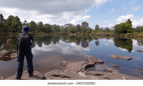 Man with backpack face to lake