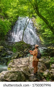 Man With Backpack Hiking In In The Forest On Summer Vacation Trip. Man Enjoying Beautiful Waterfall. Crabtree Falls Just Off The Blue Ridge Parkway. Blue Ridge Mountains, North Carolina, USA.