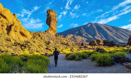 Man with backpack hiking with scenic golden hour sunrise morning view on unique rock formation Roque Cinchado, Roques de Garcia, Tenerife, Canary Island, Spain, Europe. Pico del Teide volcano summit - Powered by Shutterstock