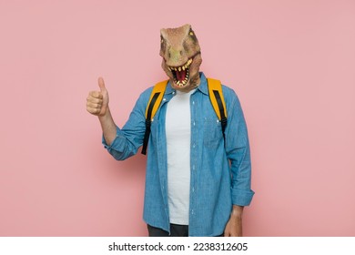 Man with backpack and lizard mask on pink background.