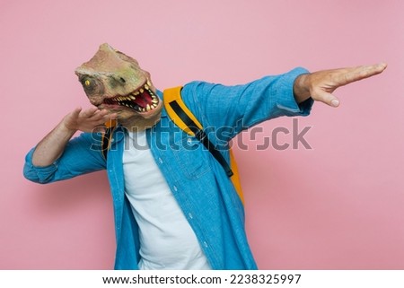Man with backpack and lizard mask on pink background.