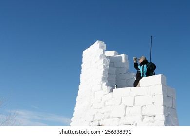 The man with a backpack looking afar from top of snow fortress