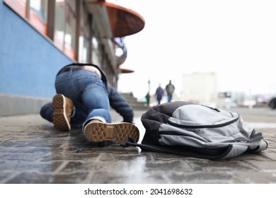 Man With Backpack Lying On Slippery Sidewalk After Fall Closeup