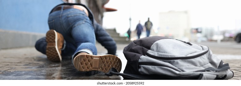 Man With Backpack Lying On Slippery Sidewalk After Fall Closeup