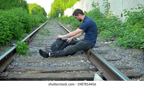 A Man With A Backpack On His Back Sat Down To Rest On The Rails. Travel On Railroad Tracks. Old Train Track 4k