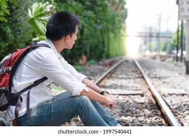 A Man With A Backpack On His Back Sat Down To Rest On The Rails. Travel On Railroad Tracks. Old Train Track, Vacation Concept.