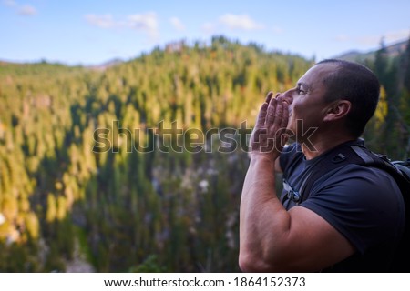 Man with backpack shouting to hear echo from the other side of the mountains