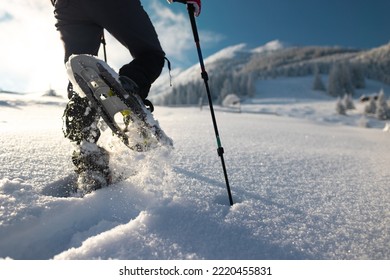 man with a backpack in snowshoes climbs a snowy mountain, winter hike, hiking equipment, snowshoes close-up