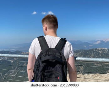 man with backpack standing on observation deck in mountains blurred background.