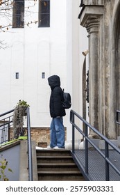 A man with a backpack standing on the steps of a building located in the old city.