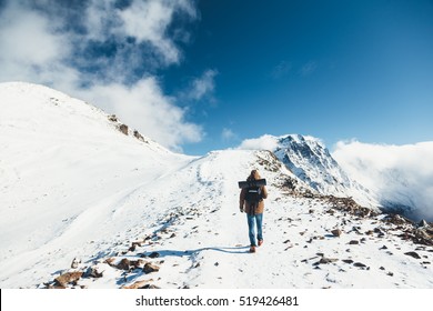 Man with backpack trekking in mountains. Cold weather, snow on hills. Winter hiking. - Shutterstock ID 519426481