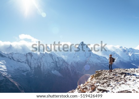Man with backpack trekking in mountains. Cold weather, snow on hills. Winter hiking.