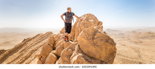 Man backpacker tourist standing mountain ridge cliff edge, looking at scenic landscape view, Negev desert travel, Israel. - Powered by Shutterstock