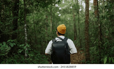 A man backpacker traveling alone in forest wild. Young man hiking trip through the green forest with backpacks. Asian man traveler explore while walking in green forest. Travel and backpack concept - Powered by Shutterstock