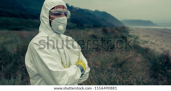 Man in bacteriological protective suit watching to\
the sea