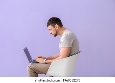 Man with bad posture using laptop while sitting on chair against color background - Shutterstock ID 1968052273