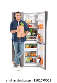 Man With Bag Of Groceries Near Open Refrigerator On White Background