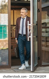 Man With Bag Touching Door Leaving Building