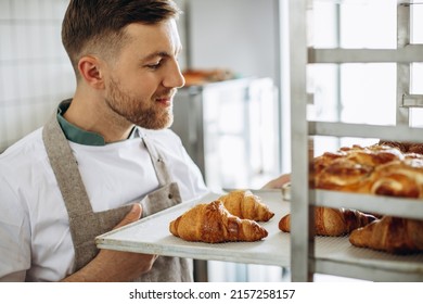 Man baker holding croissants at the bakehouse - Powered by Shutterstock