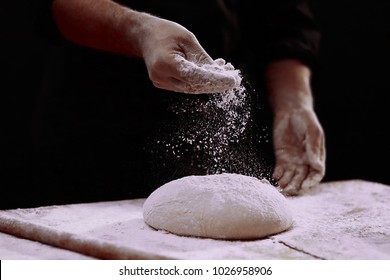 Man baking bread. Sprinkling some flour on dough. Hands kneading dough. - Powered by Shutterstock