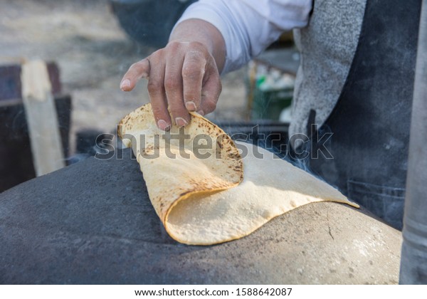 Man baking a traditional Druze Pita bread, on a Saj\
or Tava