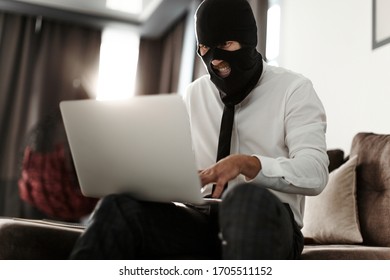 A Man In A Balaclava Mask And A White Office Shirt, Sitting At A Laptop And Trying To Anonymously Go Live For A Stream