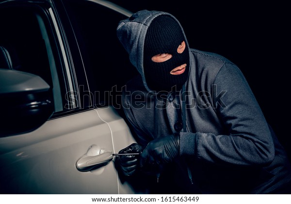 A\
man with a Balaclava on his head tried to break into the car. He\
uses a screwdriver. Hijacker, the concept of car\
theft