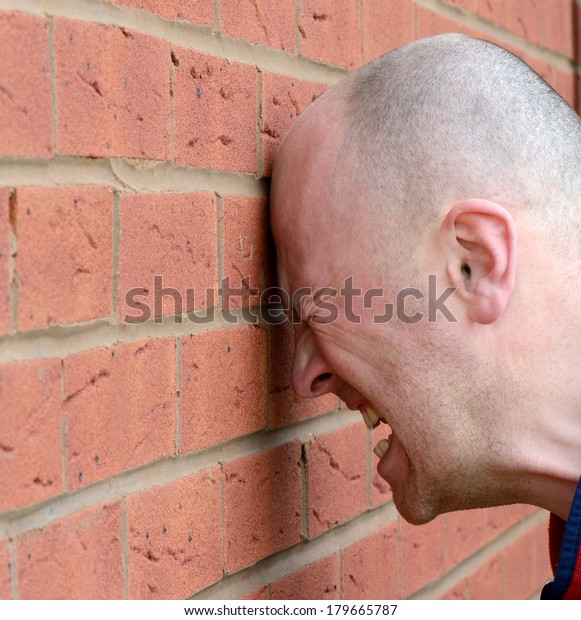 a\
man banging his head against the wall in\
frustration