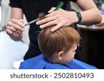 Man barber cutting little boy