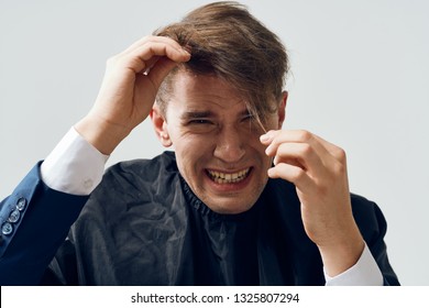 A Man At The Barber Shop Holding His Hair On A Gray Background With A Bad Haircut