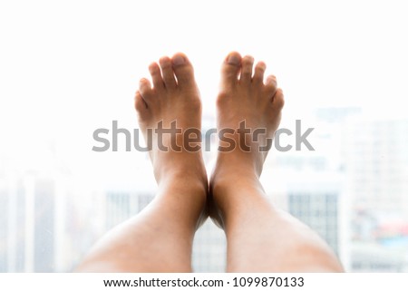 Man bare feet up on glass window and luxury view of the Taipei city, Taiwan